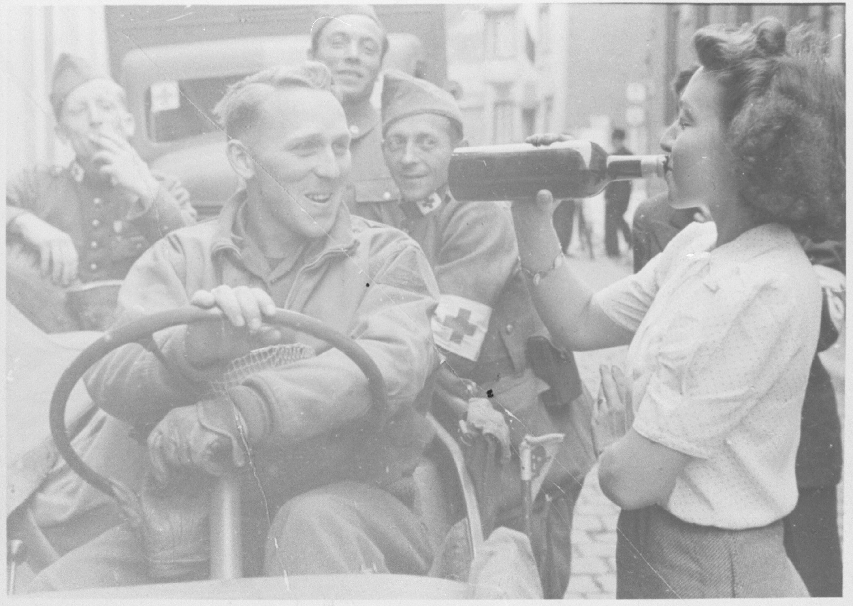 Een vrouw drinkt met geallieerde militairen op de bevrijding.